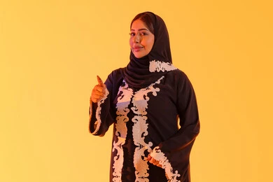 التعبير عن الجودة والاتقان، سيده سعوديه تشير بتعابير الرضي والموافقة ، البشاشة والشعور بالسعادة ،بورتريه لامراه عربيه خليجيه اماراتيه ترتدي العباءه والحجاب تقوم برفع ايديها بإيماءات الجودة والامتياز والتميز