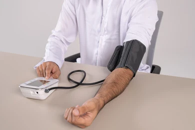 العناية والاهتمام والحفاظ على الصحة, المتابعة الدورية لفحص الدم, بورتريه مقرب لرجل عربي خليجي اماراتي يرتدي الكندورة الاماراتية يقوم بقياس ضغط الدم باستخدام الميزان الالكتروني, مفهوم الطب والرعاية الصحية, خلفية بيضاء