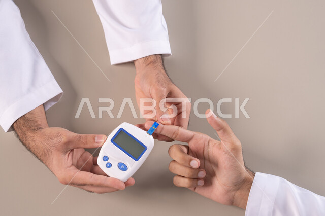 الأجهزة الالكترونية الحديثة لمرضى داء السكري, مشاكل ارتفاع السكر في الدم, الالام الجسدية والحالات المرضية, بورتريه مقرب علوي لأيدي رجل عربي خليجي اماراتي يقوم بفحص نسبة السكر في الدم, الرعاية الصحية والفحص الطبي السريع, خلفية بيضاء