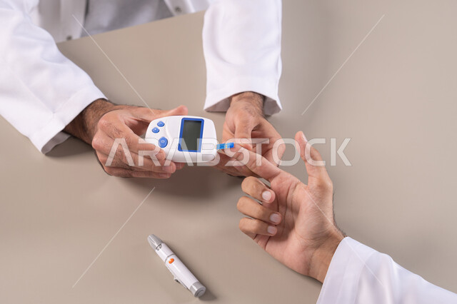 الالام الجسدية والحالات المرضية, مشاكل ارتفاع السكر في الدم, بورتريه مقرب علوي لأيدي رجل عربي خليجي اماراتي يقوم بفحص نسبة السكر في الدم, الرعاية الصحية والفحص الطبي السريع, الأجهزة الالكترونية الحديثة لمرضى داء السكري, خلفية بيضاء