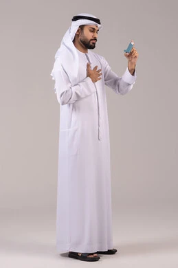 المحافظة على ممر هوائي منتظم، مشاكل في الجهاز التنفسي، بورتريه لرجل عربي خليجي اماراتي يرتدي الكندورة والغترة الاماراتية يحمل بيده جهاز الرذاذ الخاص بمرض الربو، أجهزة استنشاق المخصصة للمرضى، صورة الجسم بالطول الكامل, خلفية بيضاء
