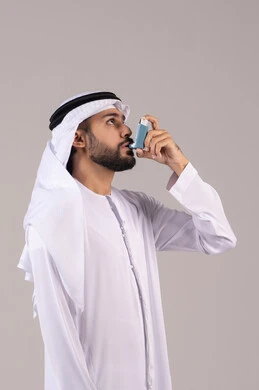 Inhalers designed for patients, maintaining an open airway, respiratory issues, a portrait of an Emirati Gulf Arab man wearing the kandura and Emirati ghutrah holding an asthma nebulizer in his hand, white background.