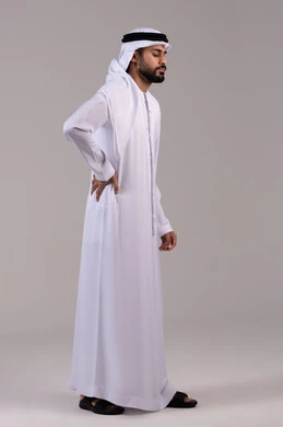 Fatigue and exhaustion and the need for treatment, joint and muscle diseases, requesting help to go to the doctor, feeling pain in the spine, a side portrait of an Arab Gulf Emirati man wearing a kandura and ghutrah feeling pain in the lower back, full body length, white background.