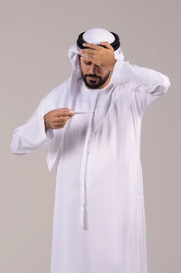 أهمية وجود ميزان رقمي في المنزل، الشعور بالإرهاق والتعب وأعراض الحمى ، بورتريه لرجل عربي خليجي اماراتي يرتدي الكندورة والغترة يمسك بيده جهاز مقياس الحرارة يقوم بقياس درجة حرارته, الحاجة إلى المساعدة الطبية, خلفية بيضاء