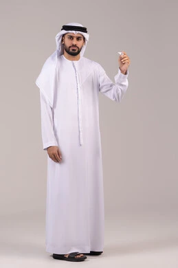 Feeling exhausted and tired with symptoms of fever, the need for medical assistance, the importance of having a digital thermometer at home, a portrait of an Emirati Gulf Arab man wearing a kandura and ghutrah holding a thermometer measuring his temperature, full-body, white background.