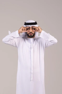 التهاب القرنية العينية، ارتفاع ضغط العين، بورتريه مقرب لرجل عربي خليجي اماراتي مريض يرتدي الكندورة والغترة يقوم بفتح عينيه باستخدام يديه، احمرار و وجع العيون، مشاكل عينيه وحالات مرضية، الحاجة للفحص والعلاج، خلفية بيضاء