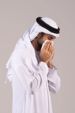 لزوم الذهاب إلى الطبيب، الشعور بالمرض و الزكام, التهاب الأنف و الجيوب التحسسية, الحاجة إلى العلاج والدواء, بورتريه من الجانب لرجل عربي خليجي إماراتي يرتدي الكندورة والغترة يضع منديل ورقي على وجهه بإيماءات العطاس, خلفية بيضاء
