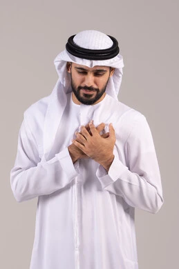 Cardiac disorders and diseases, feeling of chest pain, a portrait of a young Emirati Arab man wearing traditional attire with his hand on his chest, feeling unwell with tingling and pain, fatigue and exhaustion and psychological stress, the necessity to see a doctor for appropriate treatment, white background.
