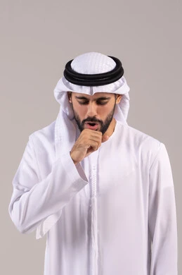 الإصابة بالأنفلونزا ونزلات البرد, إيماءات الإرهاق والتعب الشديد، الكحة والتهاب الحلق والحاجة للعلاج، بورتريه لرجل عربي خليجي اماراتي يرتدي الكندورة والغترة يضع يده أمام فمه ويقوم بالسعال, خلفية بيضاء