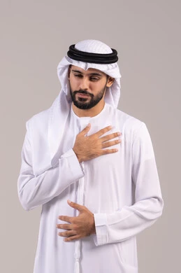 ضرورة الذهاب للطبيب لتلقي العلاج المناسب، الاحساس بذبحه صدريه، بورتريه لشاب عربي خليجي إماراتي يرتدي الزي التقليدي يضع يده على صدره، الشعور بحالة سيئة من الوخز والألم, اضطرابات وأمراض قلبية, التعب والإرهاق والضغوطات النفسية, خلفية بيضاء
