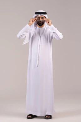 Elegance and attention to appearance, a portrait of an Arab Gulf Emirati man wearing a kandura and ghutrah holding prescription glasses, wearing glasses for vision impairment, the concept of correcting and improving vision, a full-body image, white background.