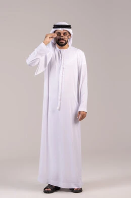 Elegance and attention to appearance, a portrait of an Arab Gulf Emirati man wearing a kandura and ghutrah holding prescription glasses, wearing glasses for vision impairment, the concept of correcting and improving vision, a full-body image, white background.