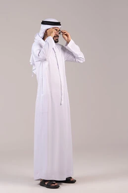 Elegance and attention to appearance, a portrait of an Arab Gulf Emirati man wearing a kandura and ghutrah holding prescription glasses, wearing glasses for vision impairment, the concept of correcting and improving vision, a full-body image, white background.