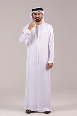 الحاجة إلى علاج سني، الشعور بآلام الفك والأسنان، الاشارة بإصبع السبابة إلى الأسنان، الوقوف باستقامة والنظر إلى الكاميرا بإيماءات التألم، مفهوم الاهتمام بالمظهر الخارجي، بورتريه لرجل عربي خليجي اماراتي يرتدي الكندورة والغترة ، الطول الكامل للجسم، خلفية بيضاء