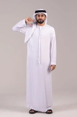 Feeling pain in the jaw and teeth, pointing with the index finger to the face, standing upright and looking at the camera with gestures of self-confidence, the concept of caring about appearance, a portrait of an Arab Gulf Emirati man wearing a kandura and ghutrah, full body length, white background.
