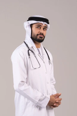 العمل في القطاع الصحي في الامارات، الفحص الطبي وتقديم الخدمات العلاجية للمرضى, الوقوف باستقامة بإيماءات الثقة بالنفس، بورتريه لطبيب عربي خليجي اماراتي يرتدي الكندورة والغترة والمعطف الطبي يضع السماعة الطبية ينظر إلى شيء ما في الاعلى، خلفية بيضاء