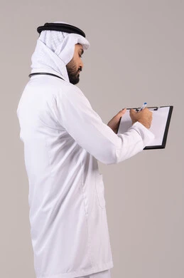 تسجيل نتائج الفحوصات بالسجل الطبي، حسن التعامل مع المراجعين، مفهوم الطب والرعاية الصحية، العمل في القطاع الصحي, بورتريه لطبيب عربي خليجي اماراتي يرتدي الكندورة والغترة والمعطف الطبي يضع السماعة الطبية يقوم بكتابة تقارير المرضى، خلفية بيضاء