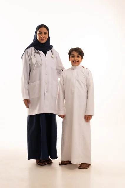 النظر إلى الكاميرا بإيماءات شكر وتقدير للطبيب، العمل في القطاع الصحي في السعودية، القيام بالرعاية الصحية والاهتمام بصحة المرضى، بورتريه  لطبيبة عربية خليجية سعودية ترتدي عباءة ومئزر أبيض وسماعة الأذن، الاهتمام بالصحة الجسدية