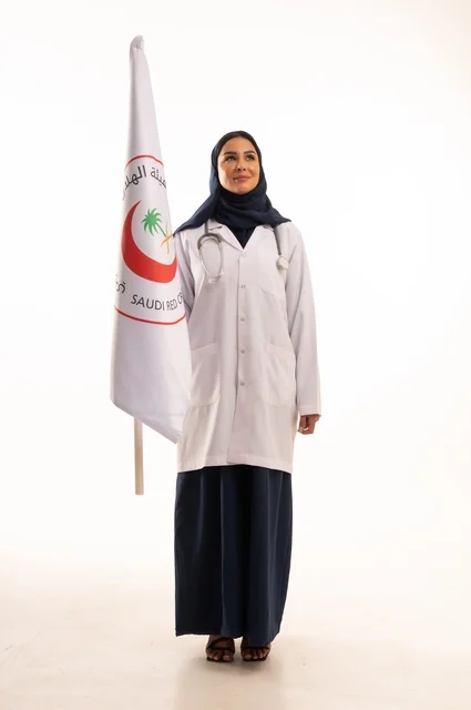 A young Saudi woman looks up with expressions of pride and honor, the concept of medicine and healthcare, a portrait of an Arab Gulf Saudi doctor wearing an abaya and a white coat holding a flag with the Red Crescent logo in her hands, marketing promotions and advertisements, white background.