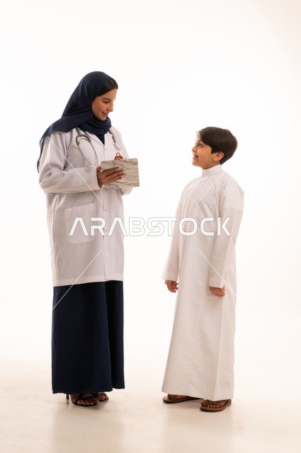 تشخيص الحالة وكتابة الملاحظات، العمل في القطاع الصحي في السعودية، القيام بالرعاية الصحية والاهتمام بصحة المرضى، بورتريه  لطبيبة عربية خليجية سعودية ترتدي عباءة ومئزر أبيض وسماعة الأذن، استخدام سماعة الطبيب لسماع نبضات القلب، الاهتمام بالصحة الجسدية