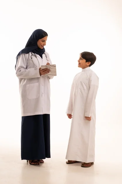 تشخيص الحالة وكتابة الملاحظات، العمل في القطاع الصحي في السعودية، القيام بالرعاية الصحية والاهتمام بصحة المرضى، بورتريه  لطبيبة عربية خليجية سعودية ترتدي عباءة ومئزر أبيض وسماعة الأذن، استخدام سماعة الطبيب لسماع نبضات القلب، الاهتمام بالصحة الجسدية