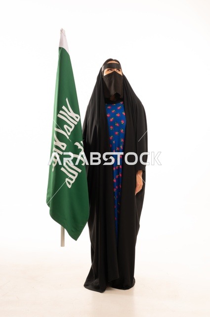Wearing traditional attire on national occasions, commemorating the Day of Foundation 1727 AD, the establishment of the first Saudi state on February 22, a portrait of an Arab Gulf Saudi woman wearing a burqa and abaya holding the flag and emblem of the Day of Foundation with expressions of pride and honor, full body length, white background.