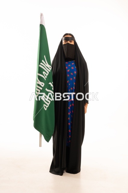 Wearing traditional attire on national occasions, commemorating the Day of Foundation 1727 AD, the establishment of the first Saudi state on February 22, a portrait of an Arab Gulf Saudi woman wearing a burqa and abaya holding the flag and emblem of the Day of Foundation with expressions of pride and honor, full body length, white background.