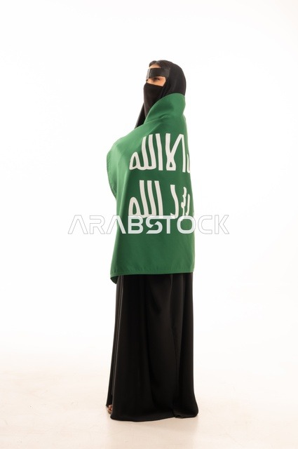 تأسيس الدولة السعودية الأولى 22 فبراير، ارتداء الأزياء الشعبية في المناسبات الوطنية, ذكرى يوم بدينا 1727 م، بورتريه لامرأة عربية خليجية سعودية ترتدي البرقع والعباءة تضع على كتفيها راية وشعار يوم التأسيس بتعابير الفخر والاعتزاز, الطول الكامل للجسم، خلفية بيضاء