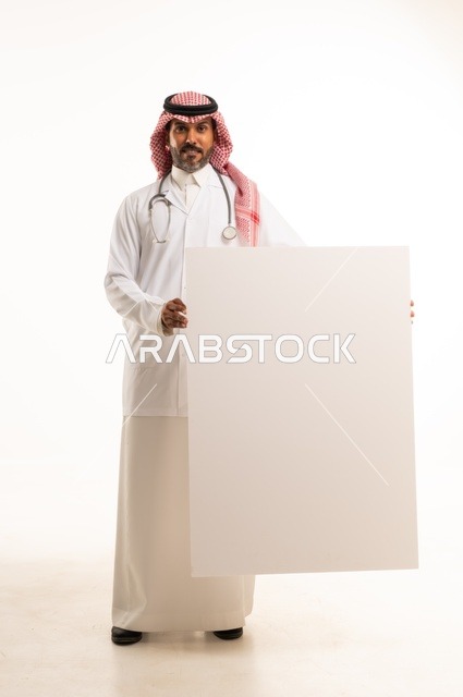 لوحات توضيحية ووسائل تعليمية, العروض والإعلانات التسويقية, بورتريه لطبيب عربي خليجي سعودي يرتدي الثوب التقليدي والمئزر الأبيض يمسك بيديه لوحة بيضاء مستطيلة فارغة، شاب سعودي ينظر إلى الكاميرا بتعابير الحزم والجدية، موك اب مستطيل أبيض, خلفية بيضاء