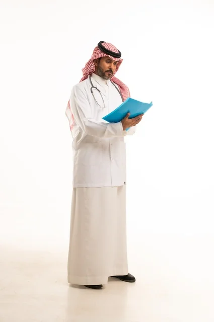 متابعة حالات المرضى والتوصيات اللازمة لكل مريض، بورتريه لطبيب عربي خليجي سعودي يرتدي الثوب التقليدي والمئزر الأبيض يمسك بيديه ملفات المرضى، شاب سعودي ينظر إلى الكاميرا بتعابير الحزم والجدية, خلفية بيضاء