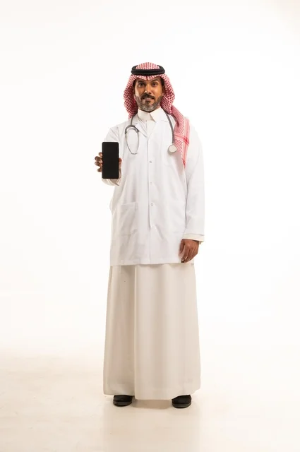عرض خلفية شاشة سوداء على الهاتف المحمول، الاهتمام بالمظهر الخارجي، تقديم الفحص الطبي والخدمات العلاجية، بورتريه مقرب لطبيب عربي خليجي سعودي مبتسم يرتدي معطف الطبيب ويضع السماعات الطبية، مفهوم الرعاية الصحية، خلفية بيضاء