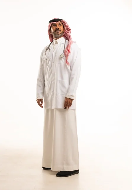 Leaning to the side, looking at the camera with gestures of self-confidence, attention to appearance, providing medical examinations and treatment services, a close-up portrait of a smiling Arab Gulf Saudi doctor wearing a lab coat and stethoscope, the concept of healthcare, white background.