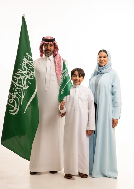 The family atmosphere filled with love, a portrait of a happy Saudi Gulf Arab family holding the Saudi flag with love and pride, celebrating Flag Day on March 11, the Saudi National Day on the 8th of Rabi' al-Awwal, the anniversary of the Saudi National Day, Saudi national holidays and occasions, white background.