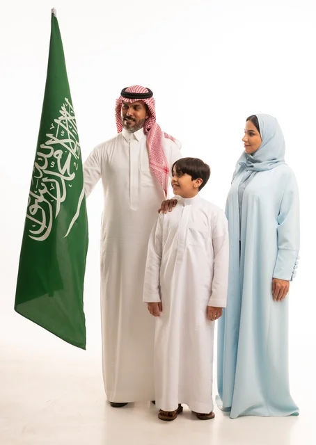 The family atmosphere filled with love, a portrait of a happy Saudi Gulf Arab family holding the Saudi flag with love and pride, celebrating Flag Day on March 11, the Saudi National Day on the 8th of Rabi' al-Awwal, the anniversary of the Saudi National Day, Saudi national holidays and occasions, white background.