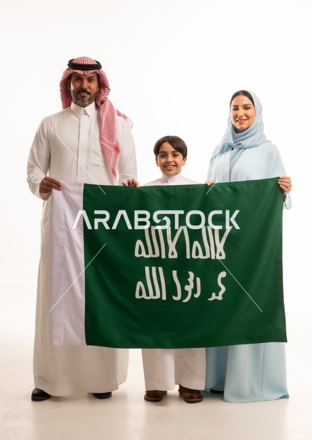 الأجواء العائلية المليئة بالحب، بورتريه لعائلة عربية خليجية سعودية سعيدة تمسك بعلم تأسيس المملكة السعودية 22 فبراير، الاحتفال بيوم العلم 11 مارس، العيد الوطني السعودي 8 ربيع الأول، ذكرى اليوم الوطني السعودي، الأعياد والمناسبات الوطنية السعودية، خلفية بيضاء