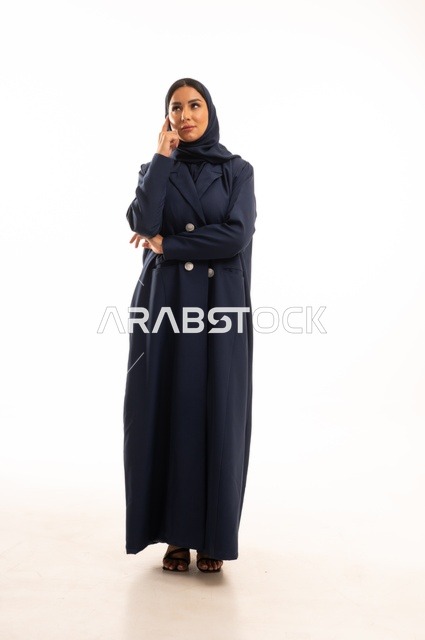 تعابير يد علىالجبهة التأمل والتفكير العميق، الاهتمام بالمظهر الخارجي والأناقة، تعابير تمني وابتسامة، بورتريه لإمرأة عربية خليجية سعودية محجبة ترتدي عباءة، شابة سعودية ،مفهوم التعبير بالإشارة، صورة الجسم بالطول الكامل، خلفية بيضاء