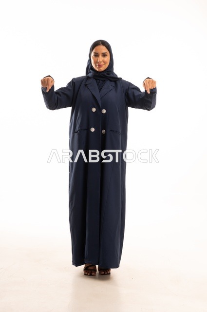 The fingers of the hands are pointing downwards, attention to external appearance and elegance, expressions of joy and a smile, a portrait of a Saudi Arabian Gulf woman wearing a hijab and an abaya, a young Saudi woman, the concept of expression through gesture, a full-body image, white background.