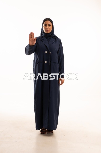 أشارة يد قف لا تكمل تعابير وجه صارمة، الاهتمام بالمظهر الخارجي والأناقة، تعابير جدية وحزم ، بورتريه لإمرأة عربية خليجية سعودية محجبة ترتدي عباءة، شابة سعودية ،مفهوم التعبير بالإشارة، صورة الجسم بالطول الكامل، خلفية بيضاء