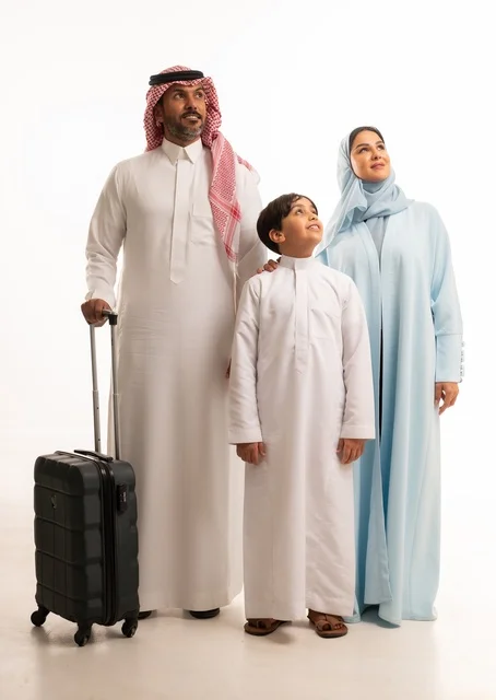 Packing a travel bag, recreational tourist activities, preparing for a trip and spending enjoyable times during the holiday with family, a portrait of a Saudi Arabian Gulf couple standing with their son with gestures of happiness and joy, maintaining family cohesion, full-body, white background.