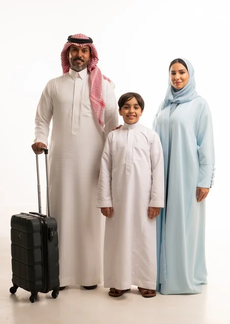 تجهيز حقيبة السفر، أنشطة سياحية ترفيهية، التأهب لرحلة سفر و قضاء اوقات ممتعة في العطلة مع الاهل، بورتريه لزوجان عربيان خليجيان سعوديان يقفان مع ابنهما بإيماءات السعادة والسرور، المحافظة على تماسك الأسرة، الجسم بالطول الكامل، خلفية بيضاء