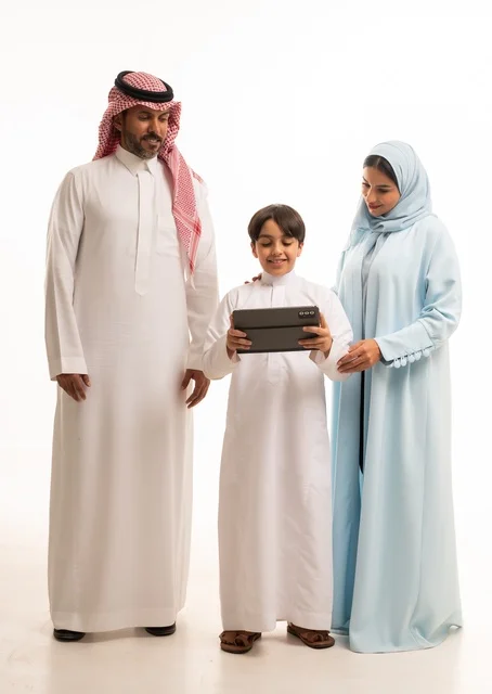 Using a modern technical device, attending online classes and making a video call through the tablet, a portrait of an Arab Saudi Gulf man wearing traditional attire holding a tablet and standing with his parents, a family atmosphere filled with love, connection, and stability, full-body shot, white background.