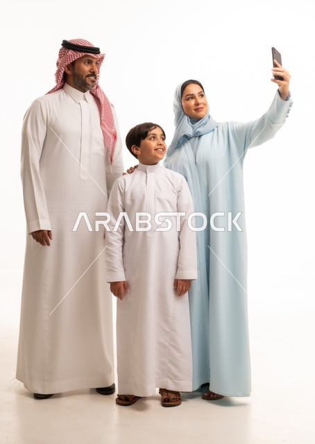 Family gathering and building a growing Saudi community, taking a memorable family selfie via mobile phone, a portrait of a smiling Arab Saudi Gulf family documenting enjoyable moments with gestures of happiness and joy, the children's joy in spending quality time with their relatives, white background.