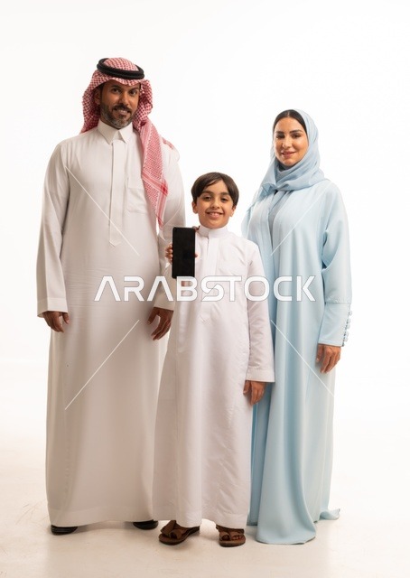 استخدام الهاتف المحمول، جهاز تقني حديث ومتطور، الاجتماع الأسري وبناء مجتمع سعودي متنامي, بورتريه لعائلة عربية سعودية خليجية مبتسمة تنظر إلى الكاميرا بإيماءات السعادة والسرور, فرحة الأبناء بقضاء وقت ممتع مع الأهل, خلفية بيضاء