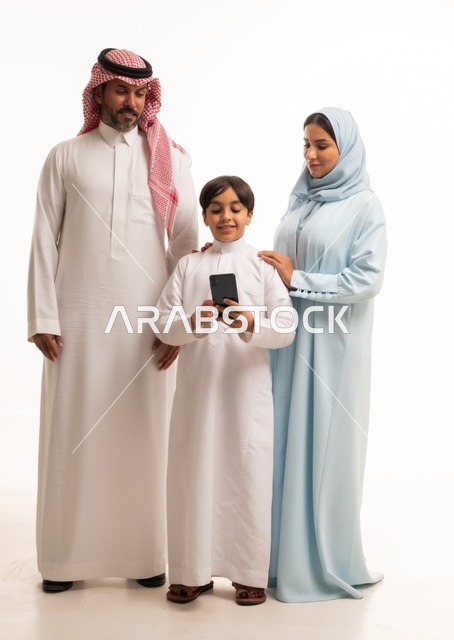 The use of mobile phones, a modern and advanced technological device, family gatherings, and building a growing Saudi community, a portrait of a smiling Arab Saudi Gulf family looking at the camera with gestures of happiness and joy, the children's delight in spending enjoyable time with their parents, white background.
