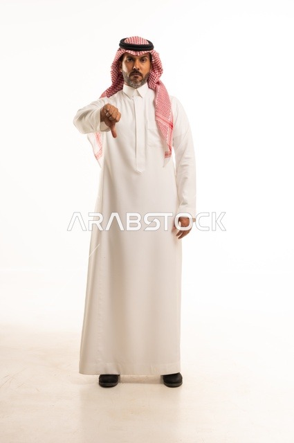 A gesture using the thumb pointing down, facial expressions of sadness, concern for appearance and elegance, expressions of displeasure and regret, a portrait of a Saudi Arabian Gulf man wearing traditional attire, a young Saudi man, the concept of expression through gesture, a full-body image, white background.