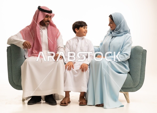 قضاء أوقات عائليه سعيده وممتعه في أيام العطله، نقاشات وحوارات الأباء مع الأبناء، بورتريه لأسره عربيه خليجيه سعودية تجلس على الاريكة وتتبادل أطراف الأحاديث، مفهوم العائله السعوديه المترابطه، بناء علاقات أسريه قويه، خلفية بيضاء.