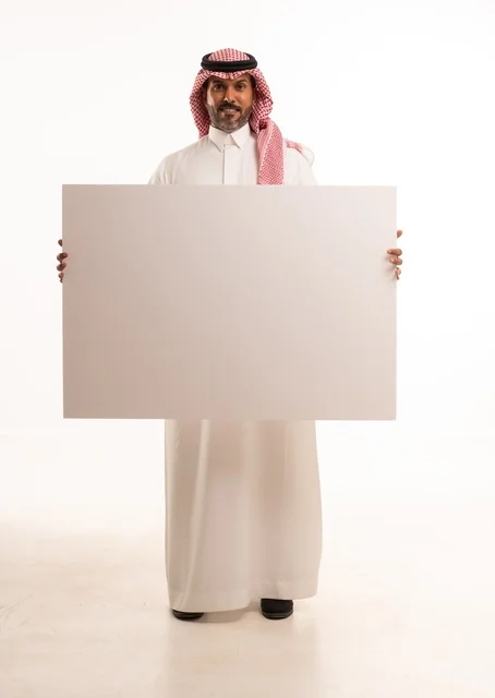 لوحات توضيحية ووسائل تعليمية, العروض والإعلانات التسويقية, بورتريه لرجل عربي خليجي سعودي يرتدي الثوب الأبيض التقليدي يمسك بيديه لوحة بيضاء مستطيلة فارغة، شاب سعودية ينظر إلى الكاميرا بتعابير الحزم والجدية، موك اب مستطيل أبيض, خلفية بيضاء