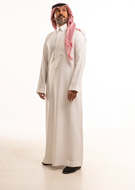 Facial expressions of a smile, hands on the side, attention to appearance and elegance, expressions of joy and happiness, a portrait of a Saudi Arabian Gulf man wearing traditional attire, a young Saudi man, the concept of expression through gestures, full-body image, white background.