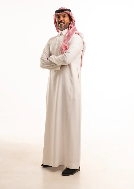 تشابك الأيدي تعابير السرور والسعادة، الاهتمام بالمظهر الخارجي والأناقة، بورتريه  جانبي لرجل عربي خليجي سعودي يرتدي الثوب التقليدي، شاب سعودي ،مفهوم التعبير بالإشارة، صورة الجسم بالطول الكامل، خلفية بيضاء