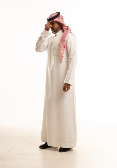 تعابيريد وضع اليد على الأنف ألم في منطقة الجيوب الأنفية، الاهتمام بالمظهر الخارجي والأناقة، بورتريه  جانبي لرجل عربي خليجي سعودي يرتدي الثوب التقليدي، شاب سعودي ،مفهوم التعبير بالإشارة، صورة الجسم بالطول الكامل، خلفية بيضاء